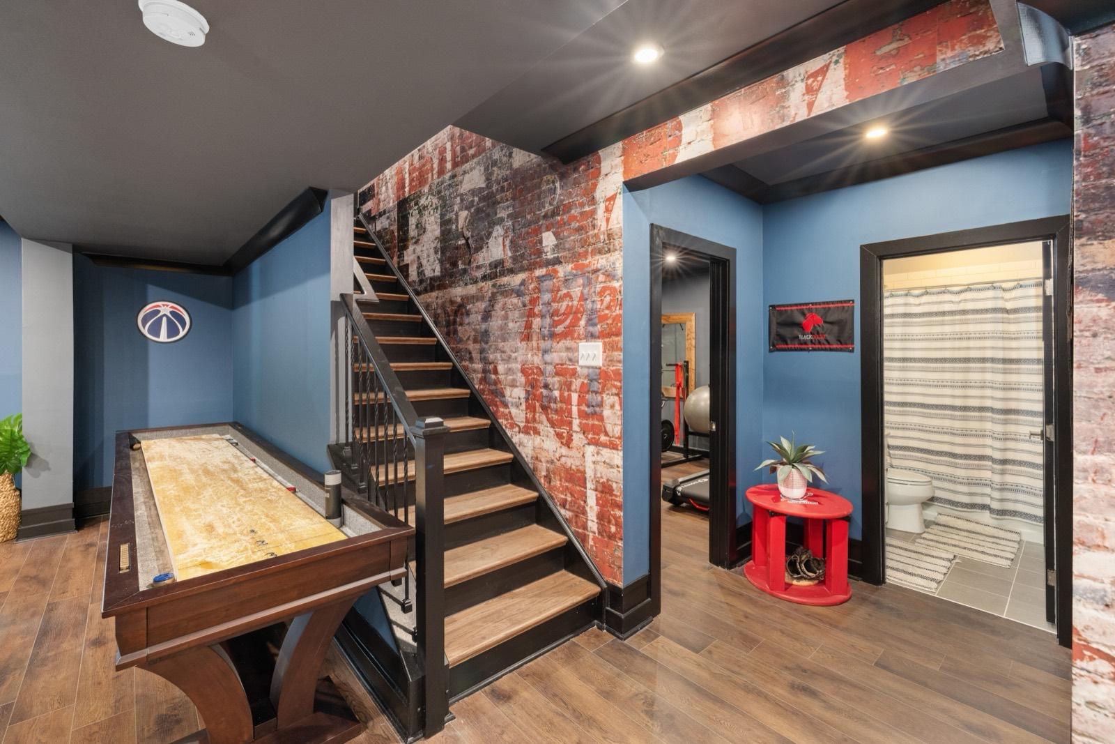 Finished basement game room with an exposed-brick accent wall — AMV Construction, Charlotte NC