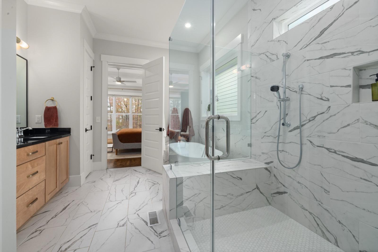 Walk-in marble-tile shower with a natural wood vanity — tile installation project by AMV Construction in Charlotte, NC