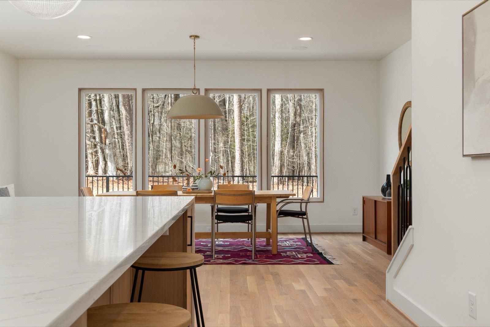 Dining nook framed by a wall of windows over hardwood floors — AMV Construction, Charlotte NC