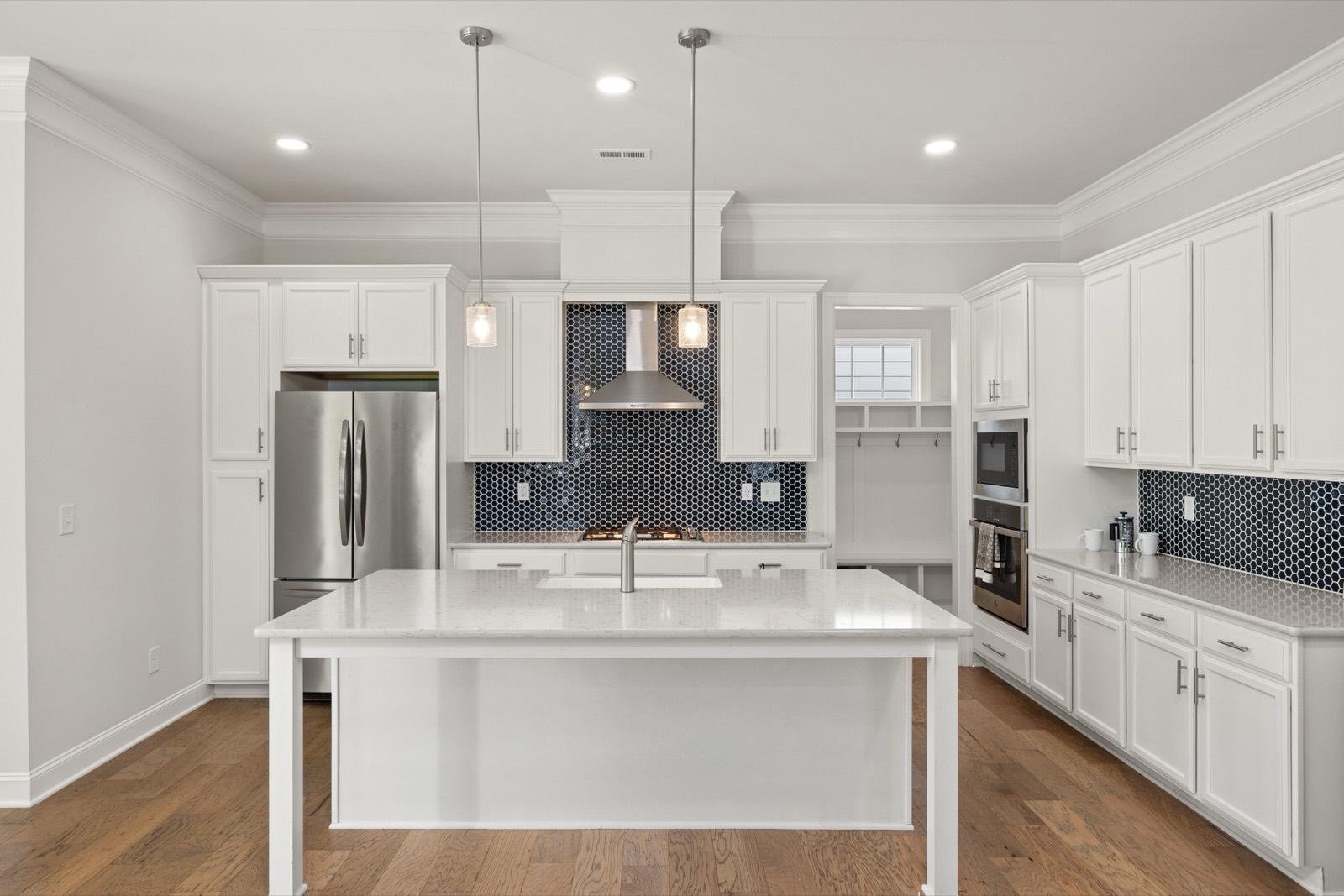 White kitchen with a navy tile backsplash and hardwood floors — AMV Construction, Charlotte NC