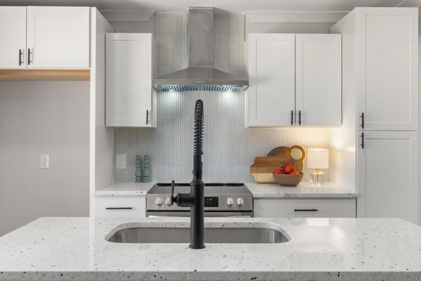 White kitchen with a stainless hood and stacked tile backsplash — tile installation project by AMV Construction in Charlotte, NC