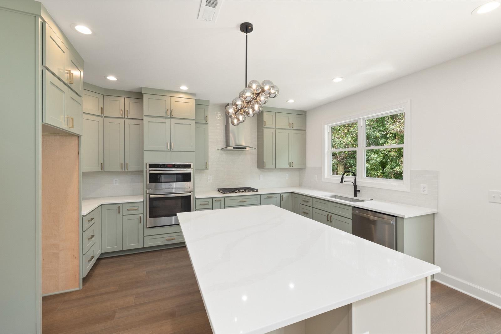 Kitchen with sage green cabinetry and a waterfall quartz island — AMV Construction, Charlotte NC