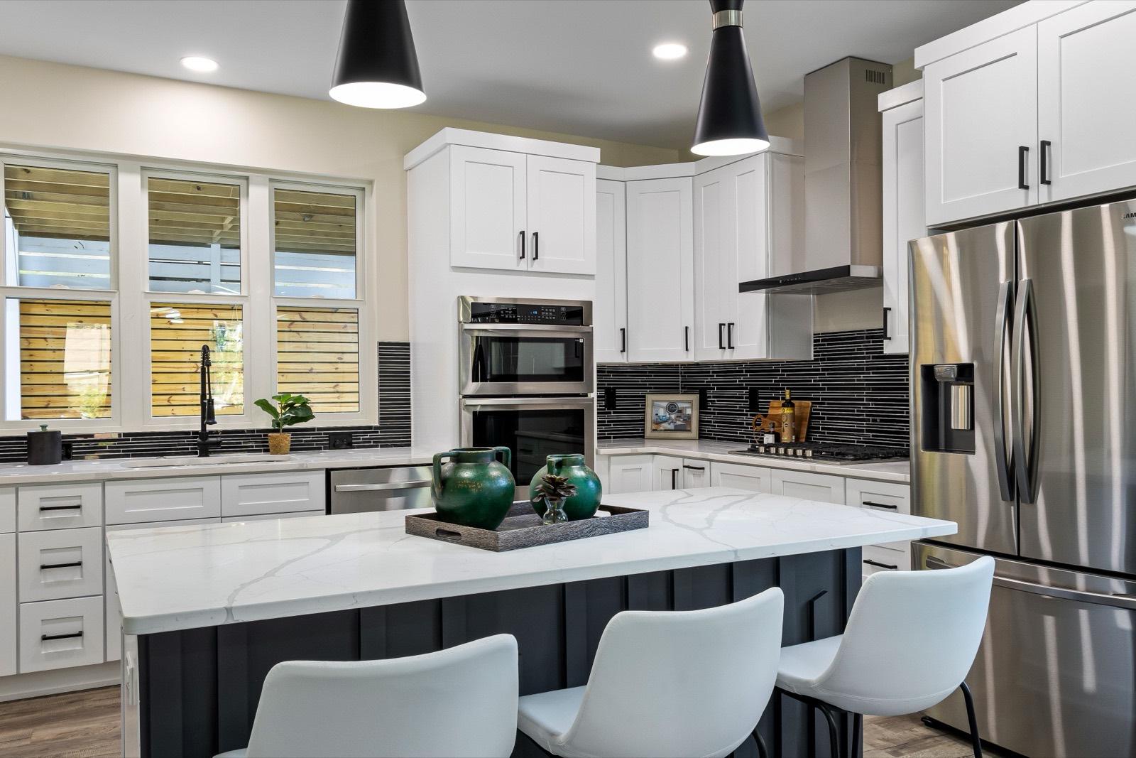 White kitchen with a quartz island and built-in double ovens — AMV Construction, Charlotte NC