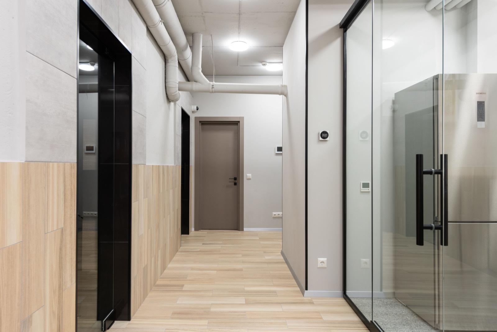 Office corridor with glass partition walls and wood-panel wainscot — AMV Construction, Charlotte NC