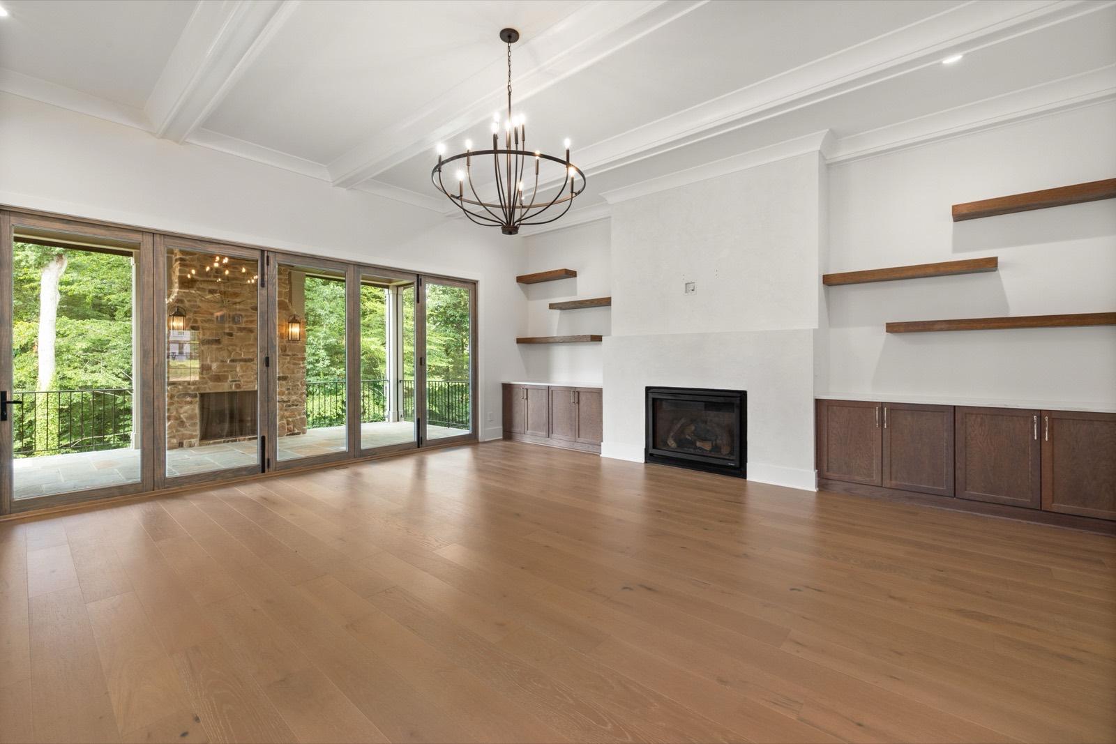 Living room with an exposed beam ceiling and wood wainscot built-ins — AMV Construction, Charlotte NC