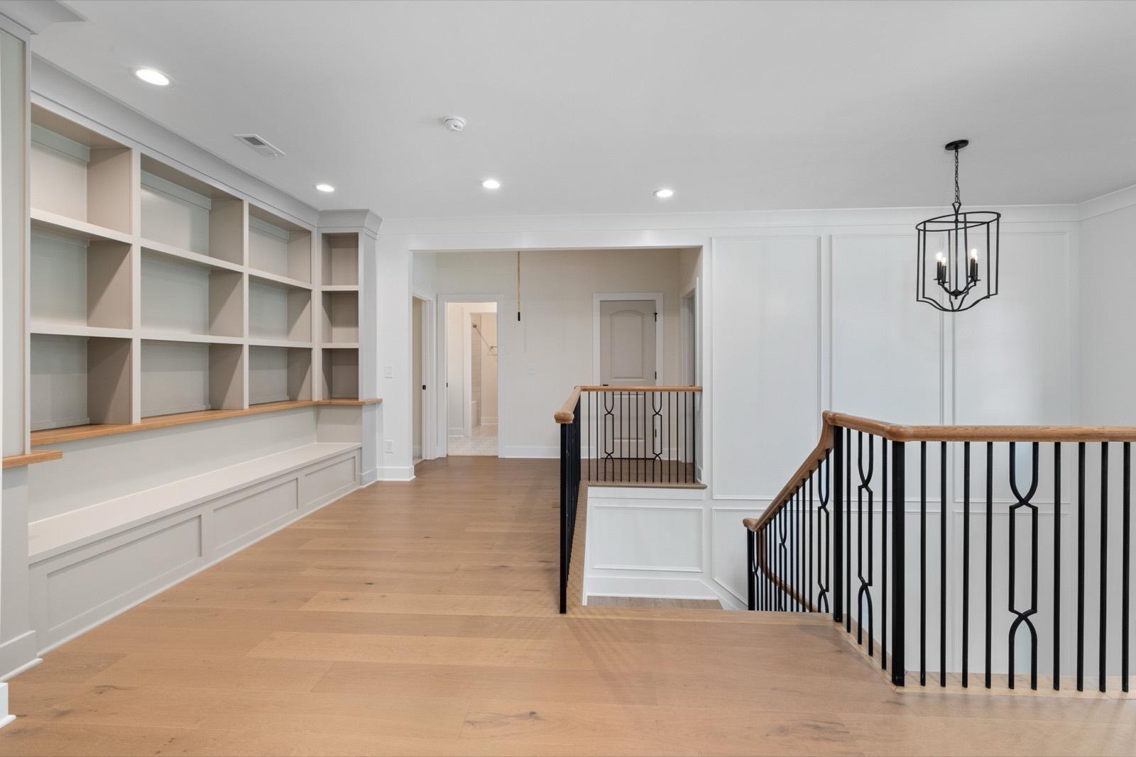 Upstairs landing with built-in shelving and a wrought-iron stair railing — AMV Construction, Charlotte NC