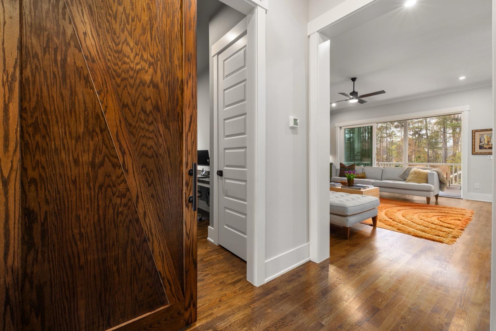 Hallway with a stained wood door, painted casing, and hardwood floors — AMV Construction, Charlotte NC